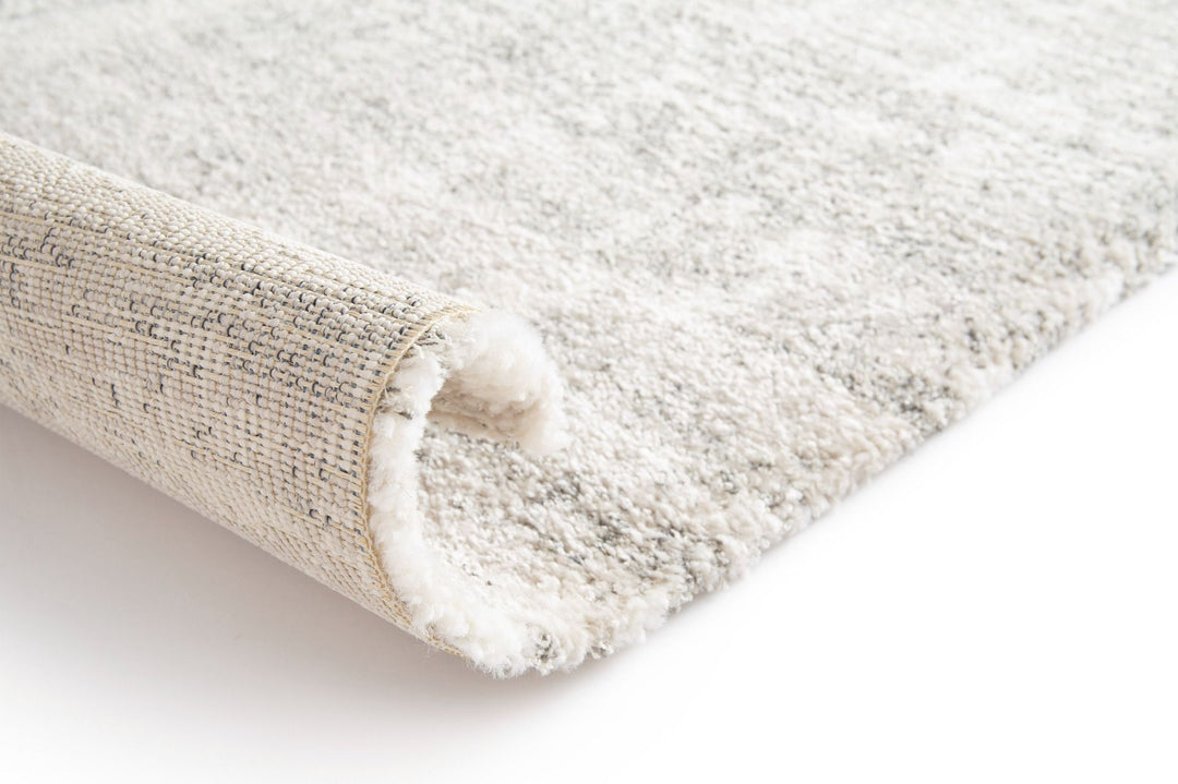 Close-up of a rolled corner of a soft textured grey rug.