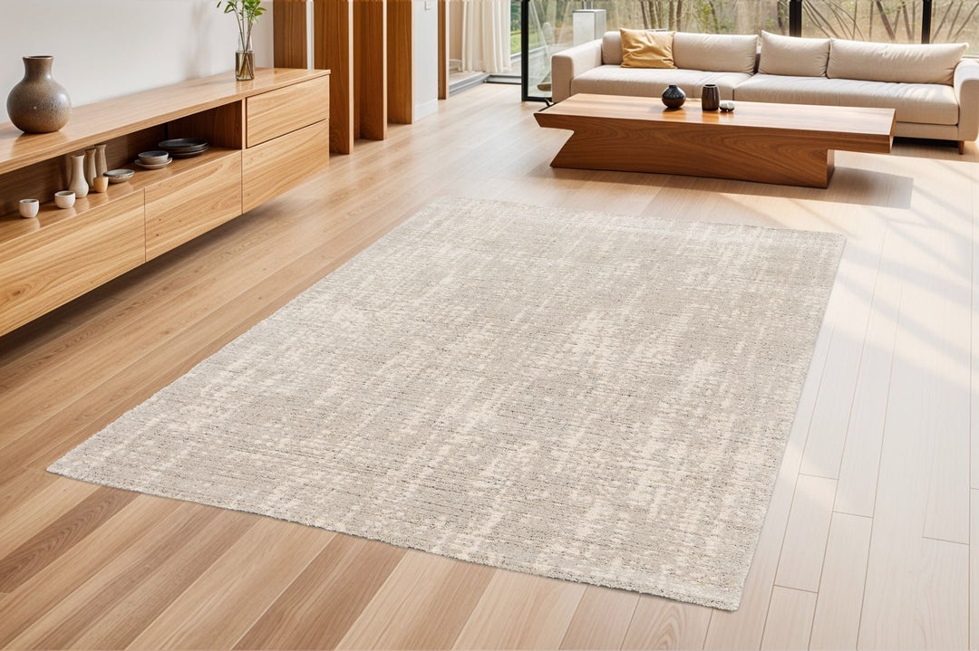 Beige rug placed in a modern living room with wood flooring.