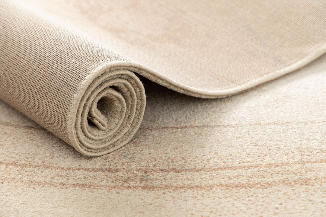 Rolled beige and brown rug showing backing and texture.