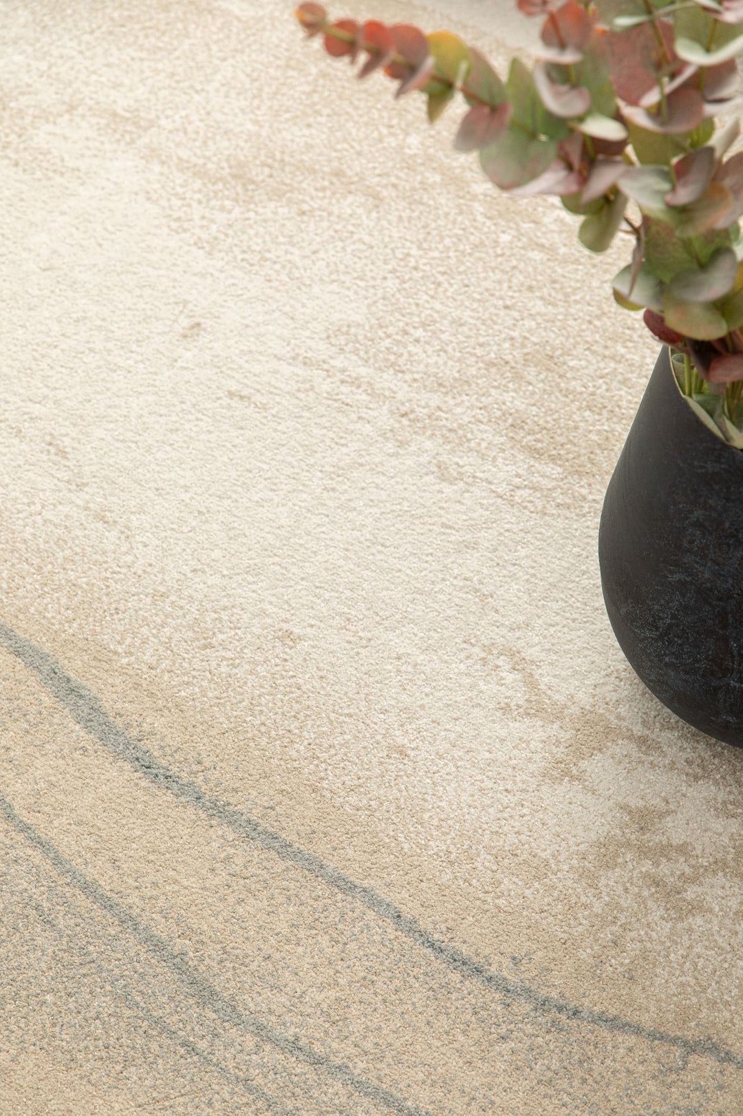 Rug corner with vase and green leaves on top.