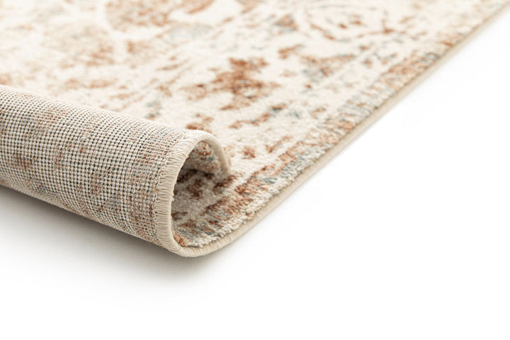 Close-up of a rolled beige and rust patterned rug corner.