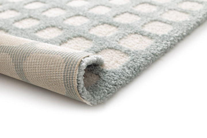 Rolled corner of a blue and white geometric rug.