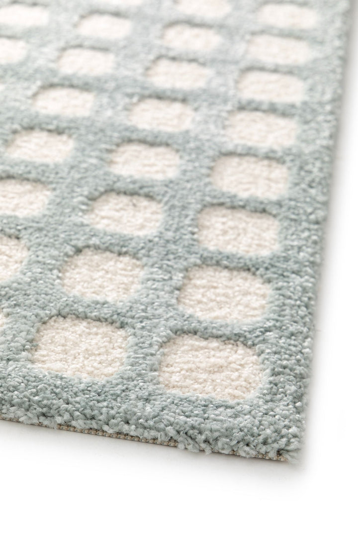 Close-up of a blue rug with white square patterns.