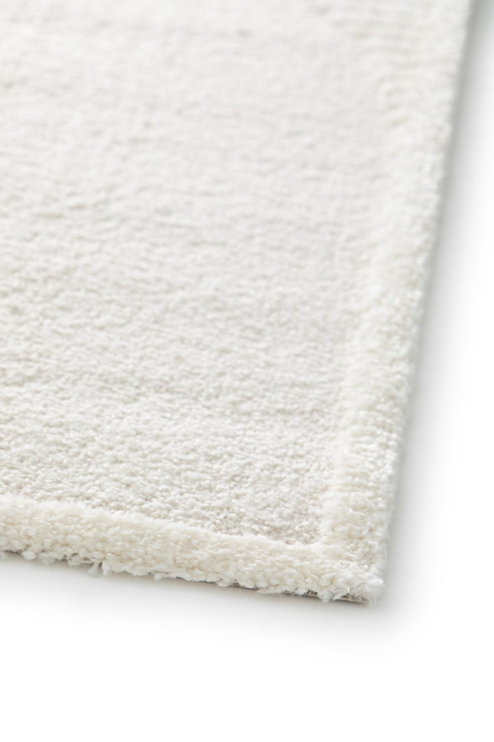 Detailed view of a cream rug edge with a soft pile.
