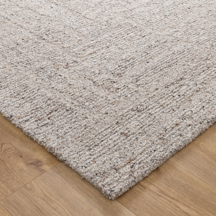 Beige wool loop rug on a wooden floor