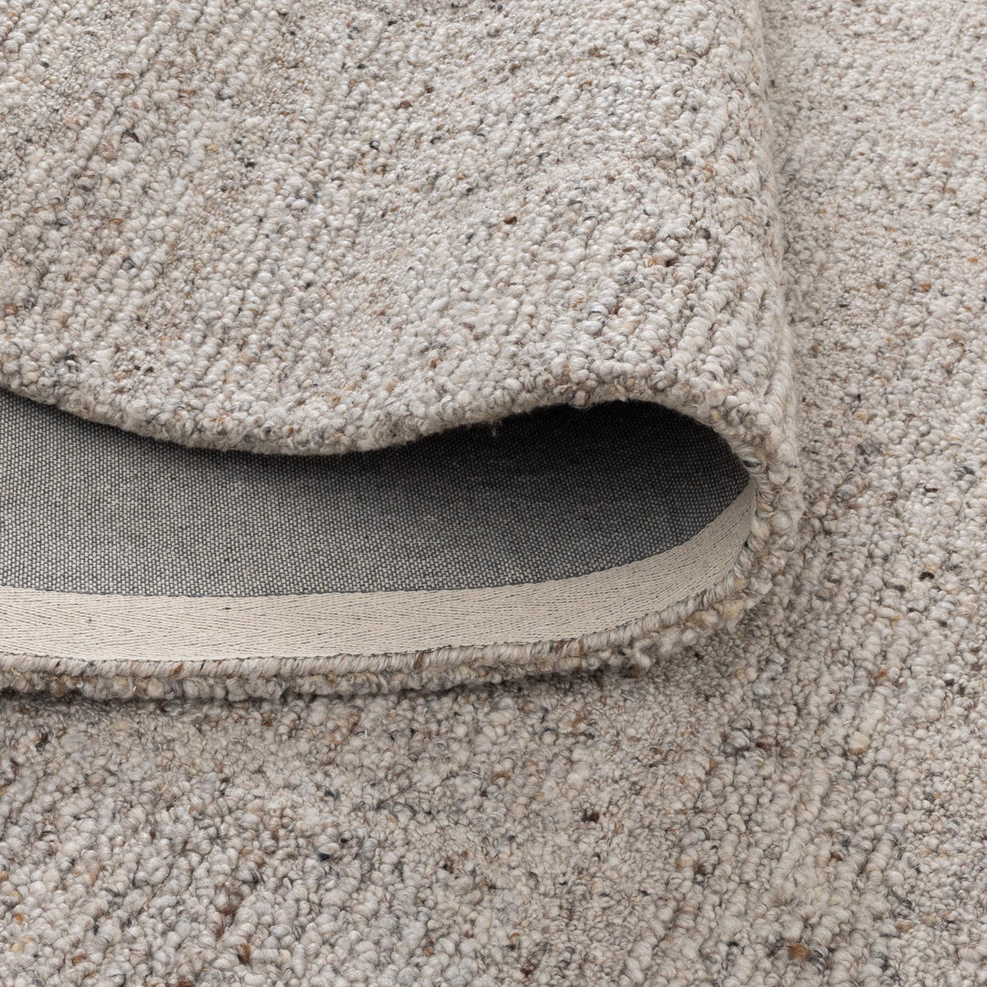Close-up of a beige textured rug with a visible border.