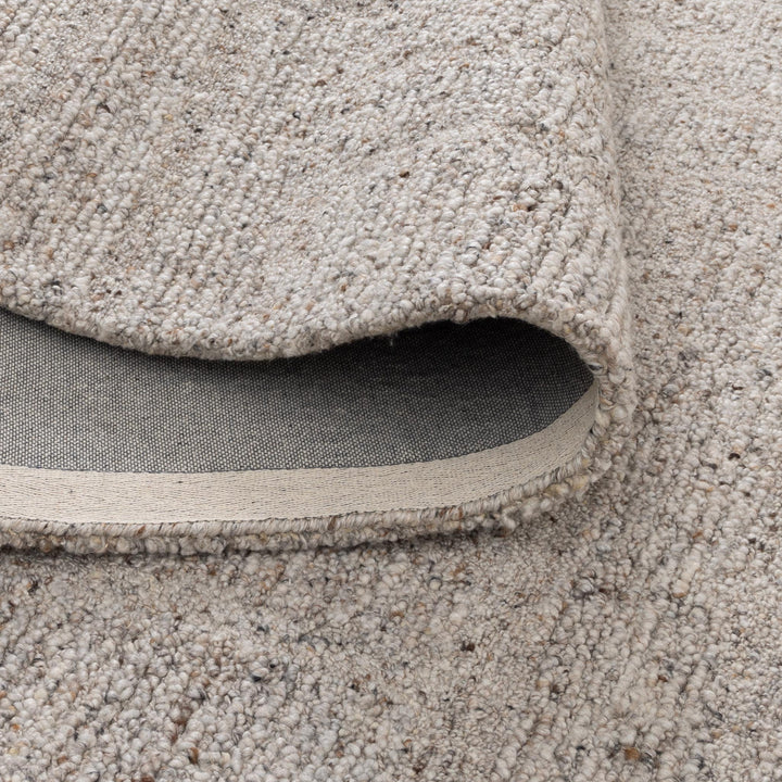 Close-up of a beige textured rug with a visible border.