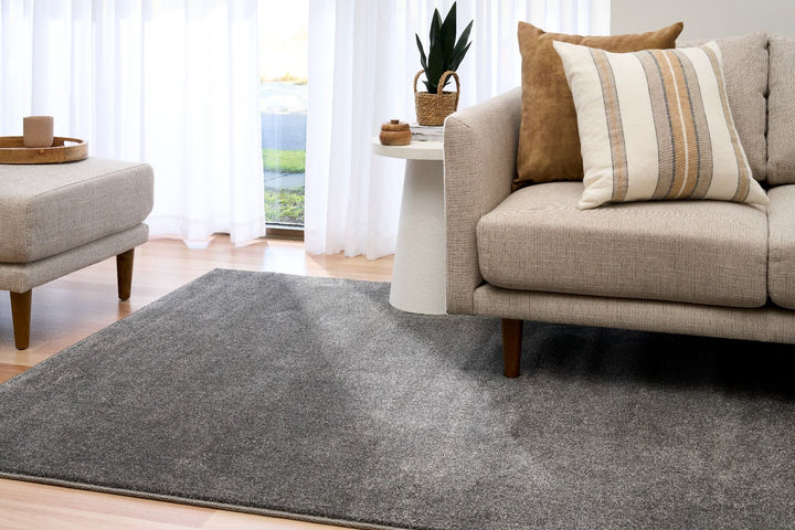 Dark grey rug corner lifted to show underside on wood floor.