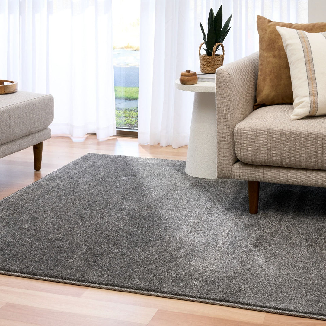 Grey rug styled in a modern living room with beige furniture.