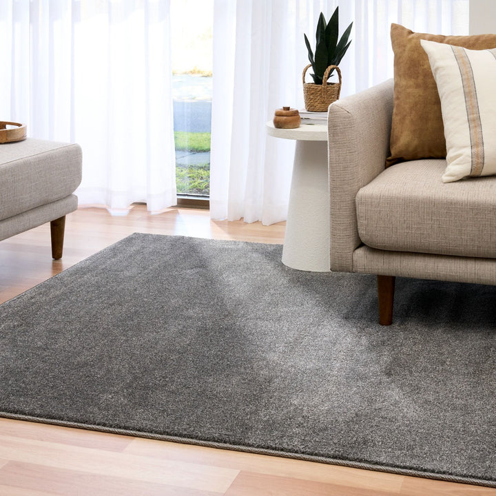 Grey rug styled in a modern living room with beige furniture.