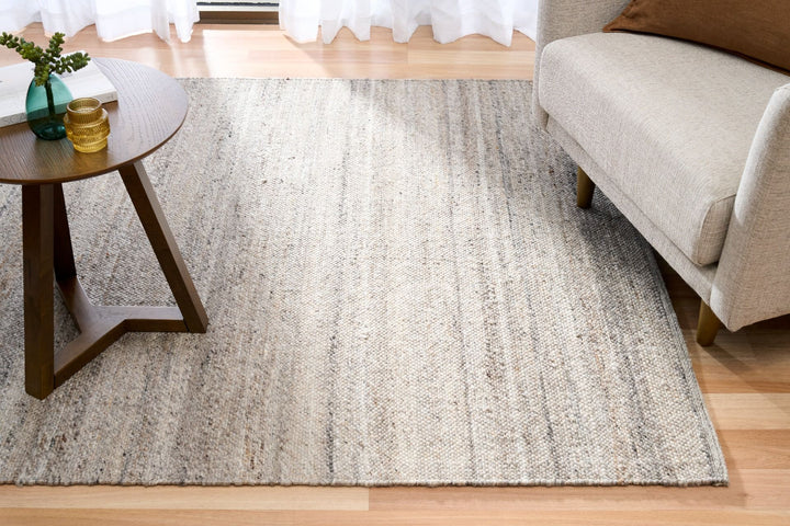 Dark grey rug styled in a living room with sofa and wooden side table