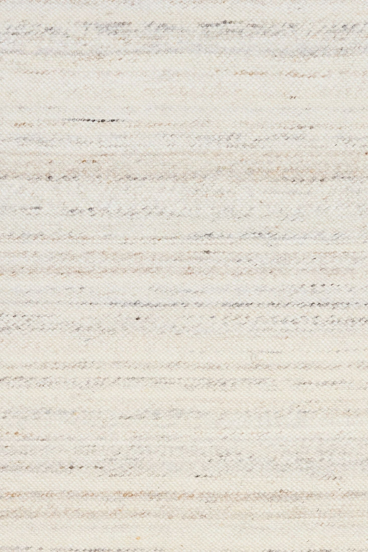 Detailed close-up of ivory woven rug texture with subtle grey and beige speckles.