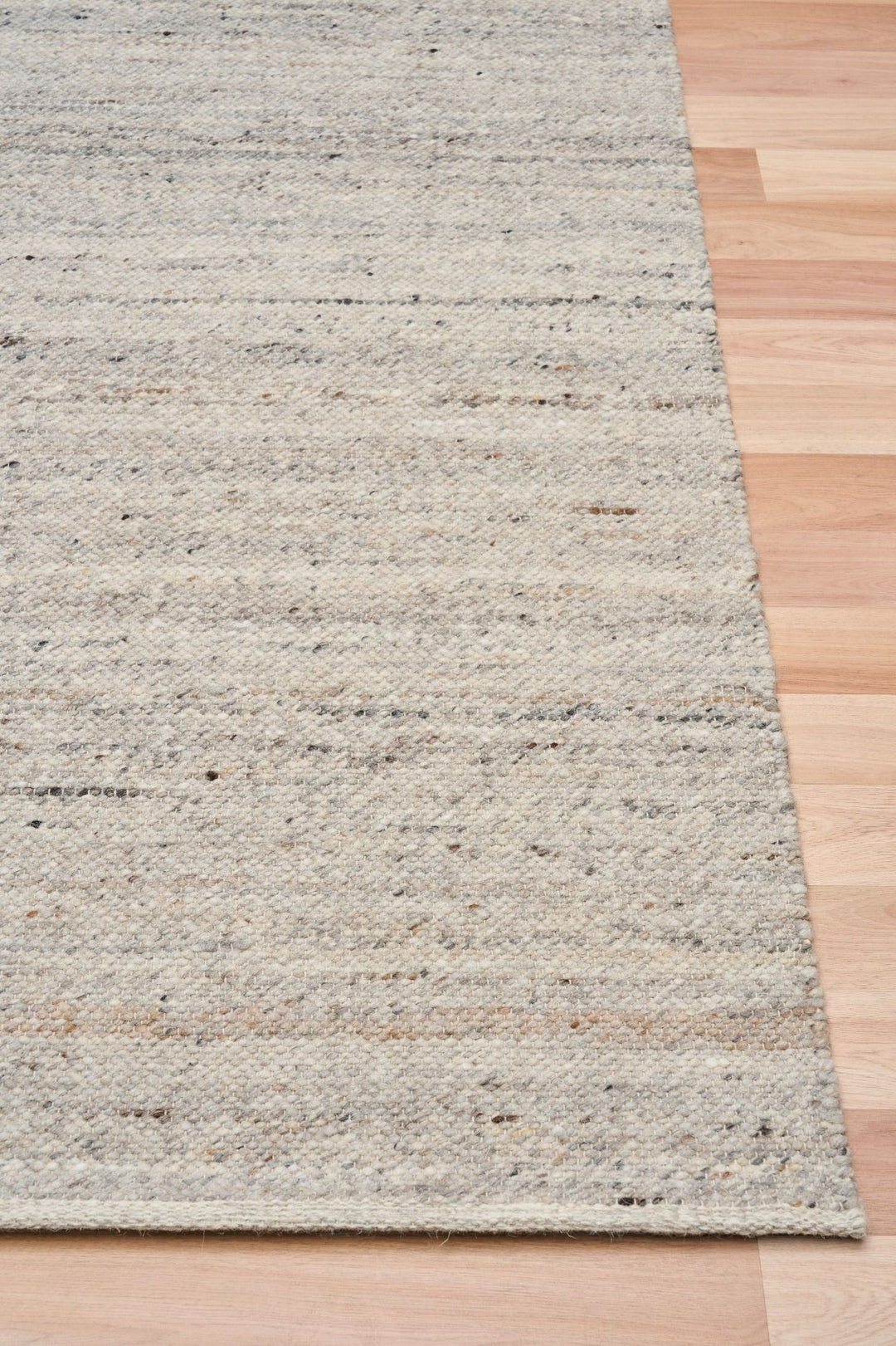 A close-up of the Harmony Smoke Grey rug corner on a wooden floor.