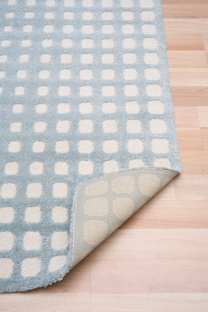Blue and white patterned rug with corner folded.