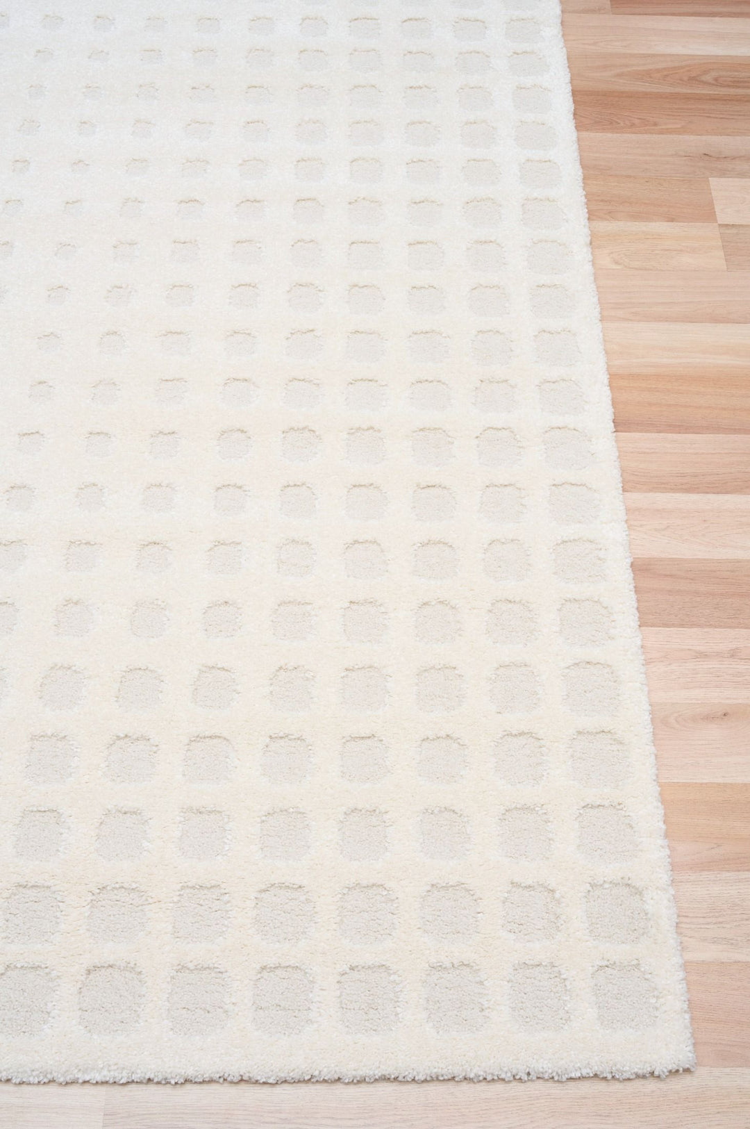 A close-up of a white rug with a raised square design.
