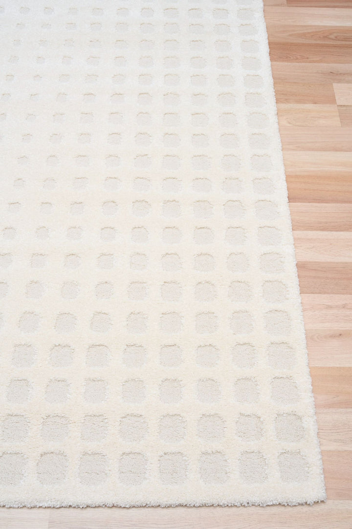 A close-up of a white rug with a raised square design.