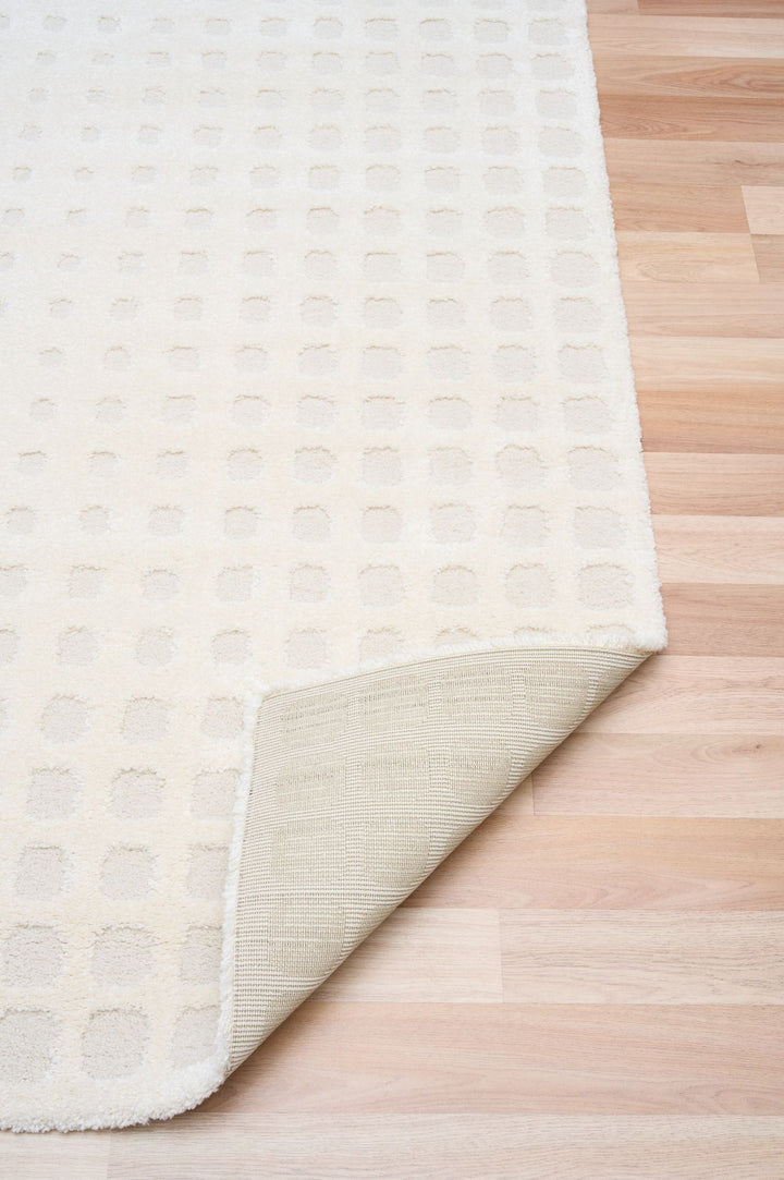 A white rug with one corner folded to show the underside.