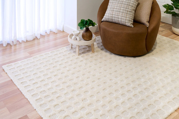 A white patterned rug styled in a living room with a brown chair.
