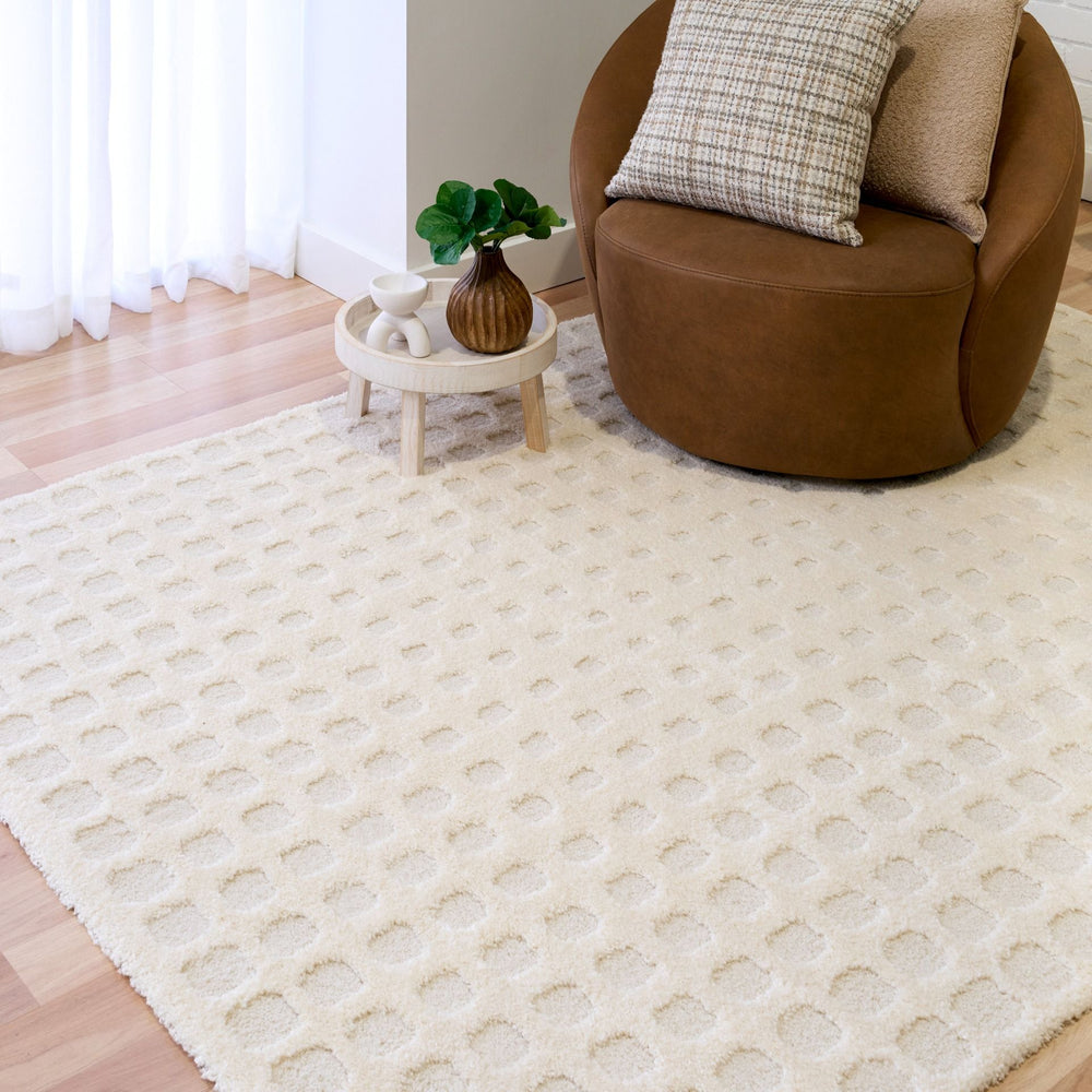 A white rug under a round chair and side table in a modern room.