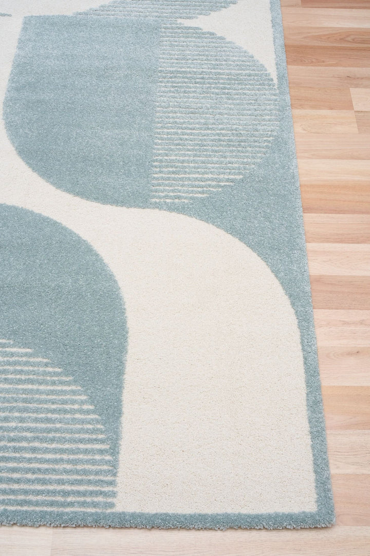Close-up of blue and cream rug edge on wooden floor.