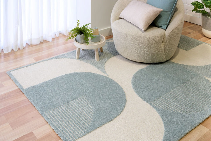 Blue and cream rug under round chair and side table.
