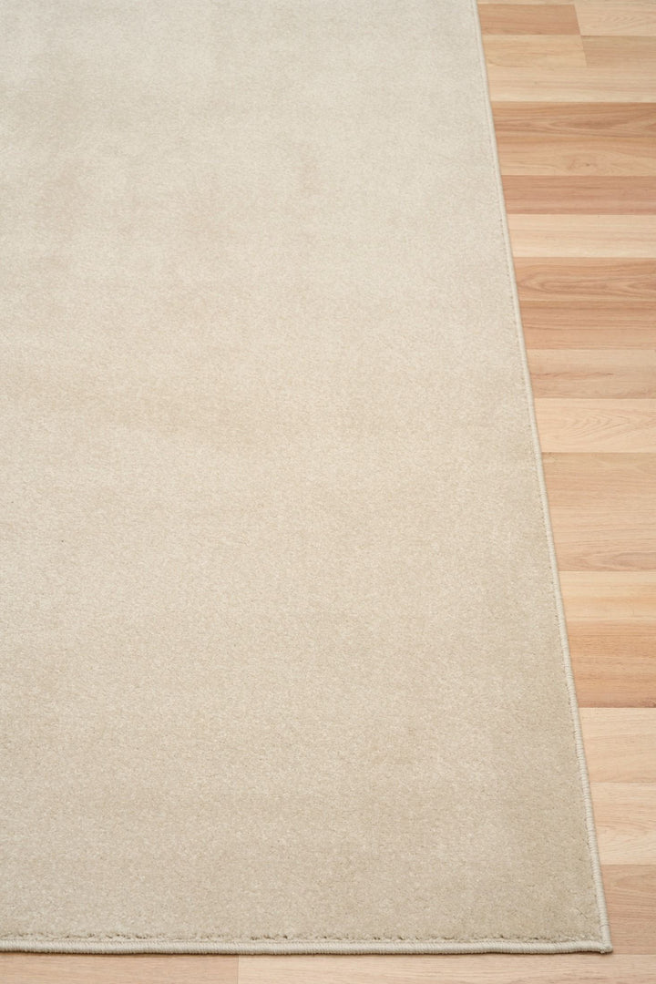 Beige rug corner on wooden floor.