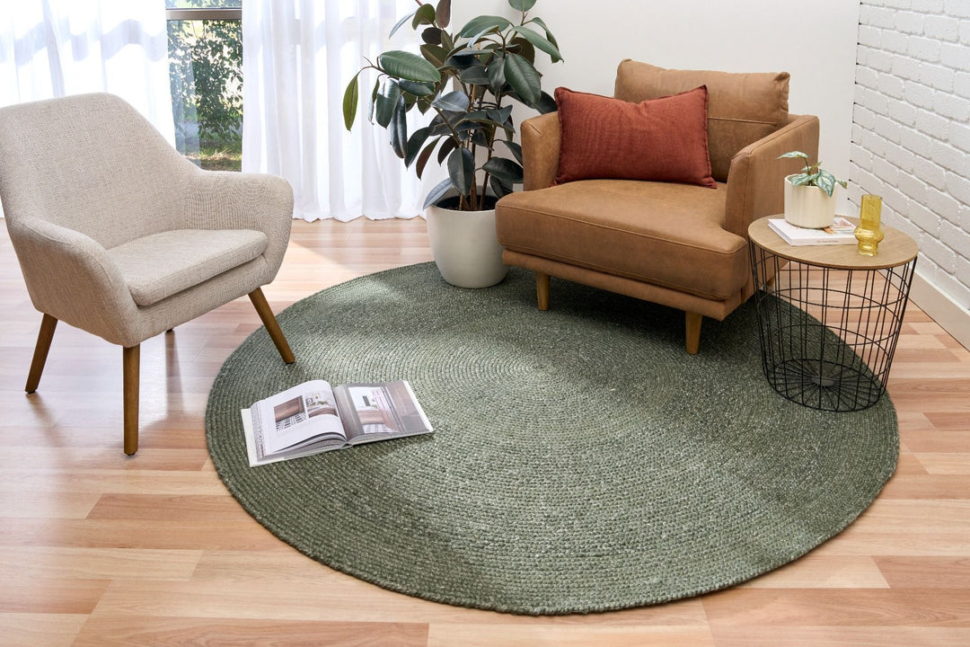 Modern living room with a green round rug, pairing a tan armchair, beige accent chair, and indoor plant for a cozy and stylish home decor look.