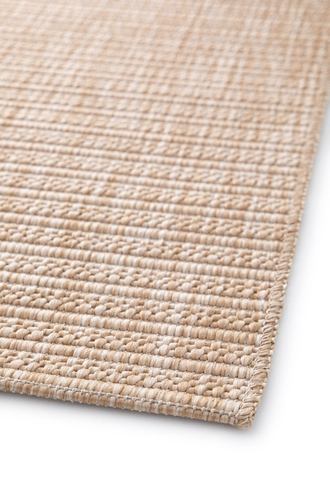 Close-up of beige woven rug with diamond lattice, stitched corner edge, and chunky texture on white
