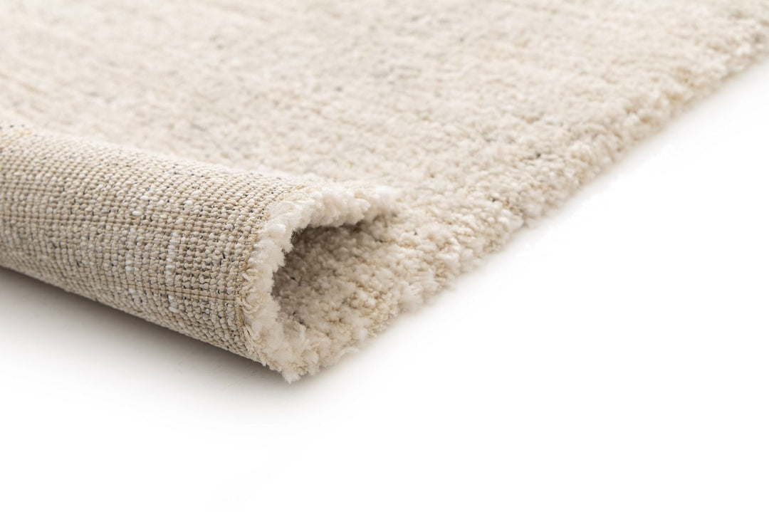 Rolled corner of beige rug.