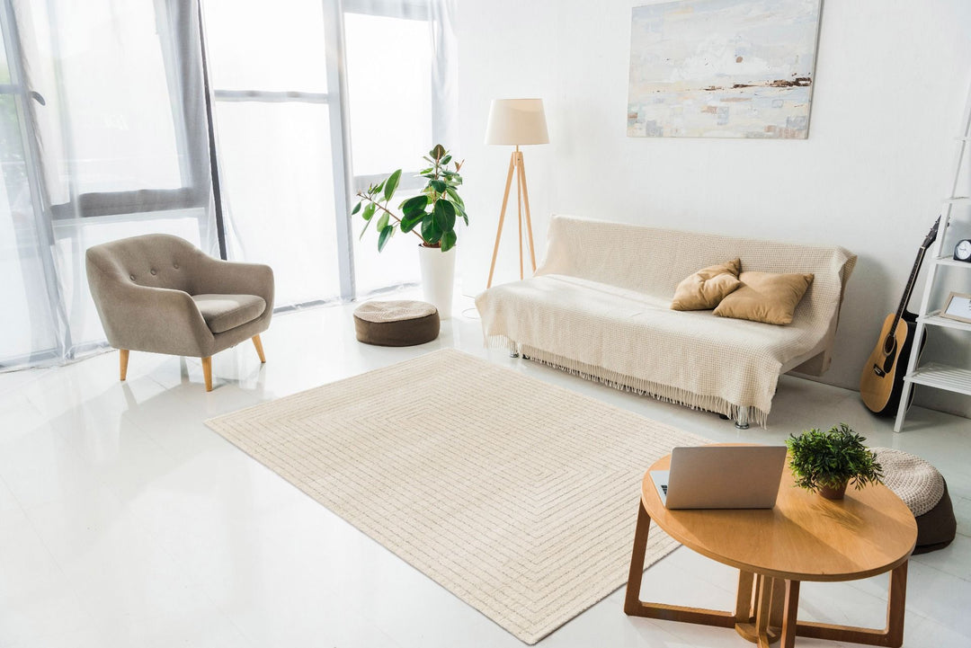 A modern living room with a beige patterned rug under neutral furniture.