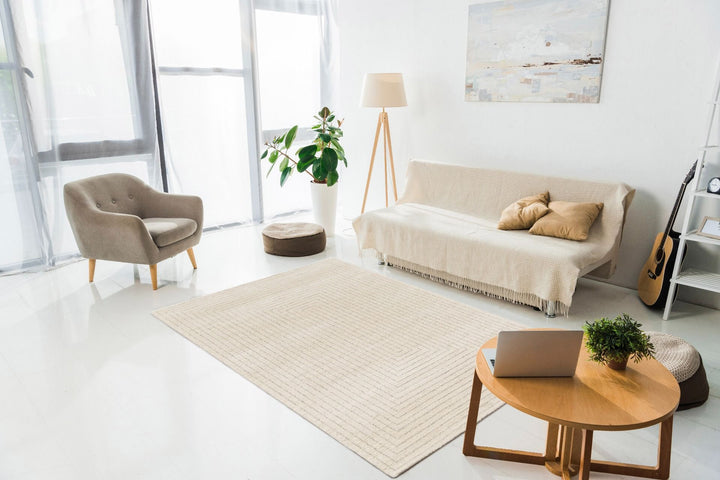 A modern living room with a beige patterned rug under neutral furniture.