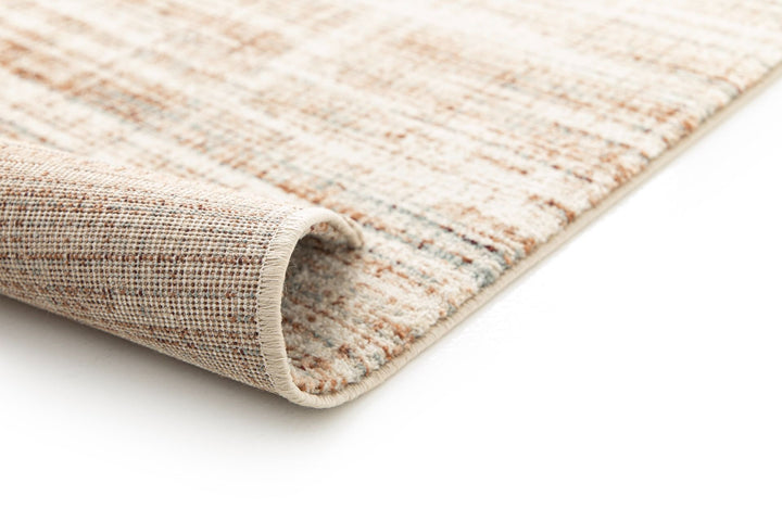 Close-up of a rolled beige and brown patterned rug edge.