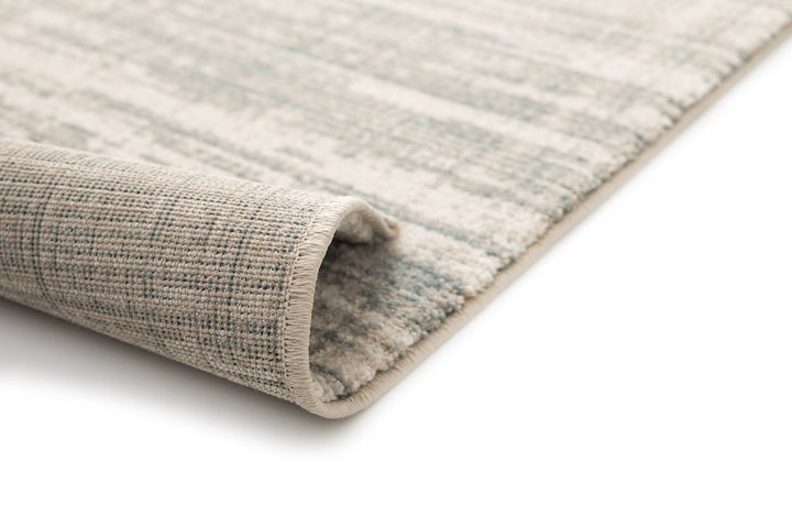 Close-up of a rolled rug corner showing its backing.