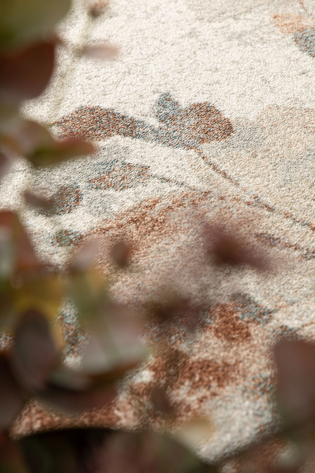 A detailed view of the rug with blurred plants in the foreground.