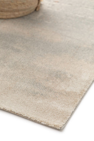 Rug corner with basket on muted abstract design.