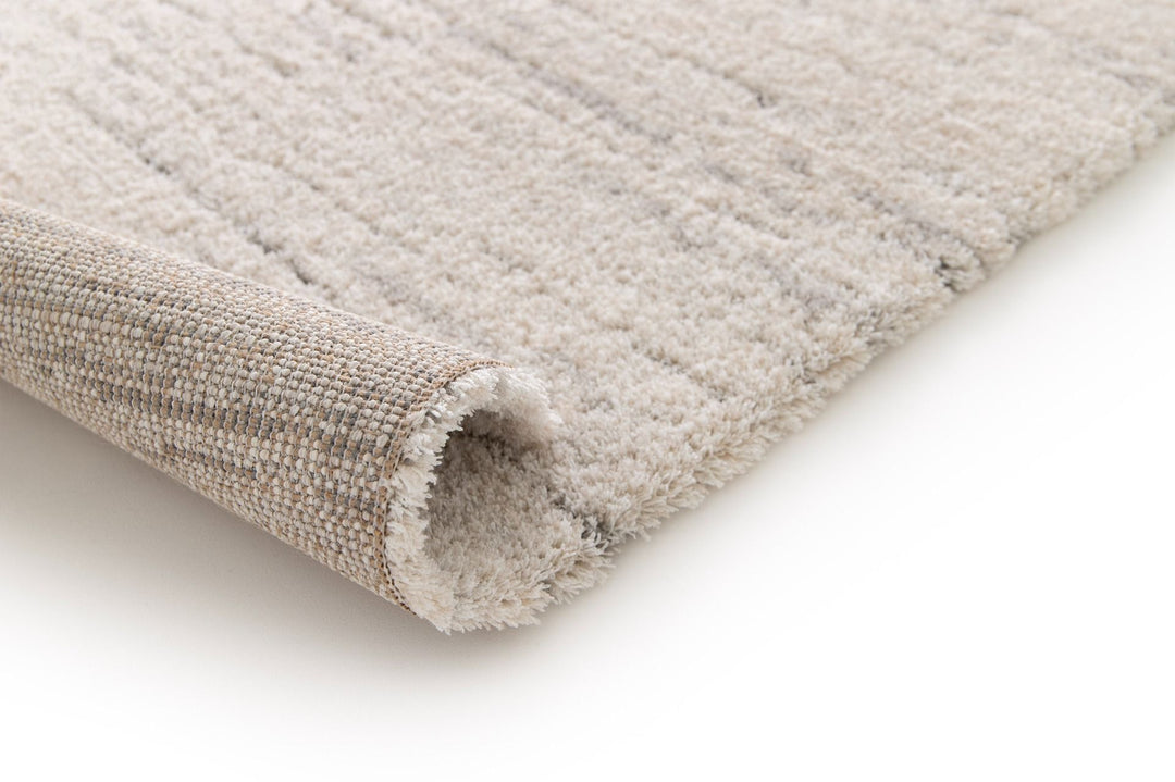 Rolled edge view of beige rug.