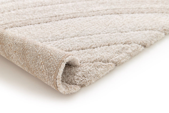 Rolled corner view of a beige rug with subtle line pattern.