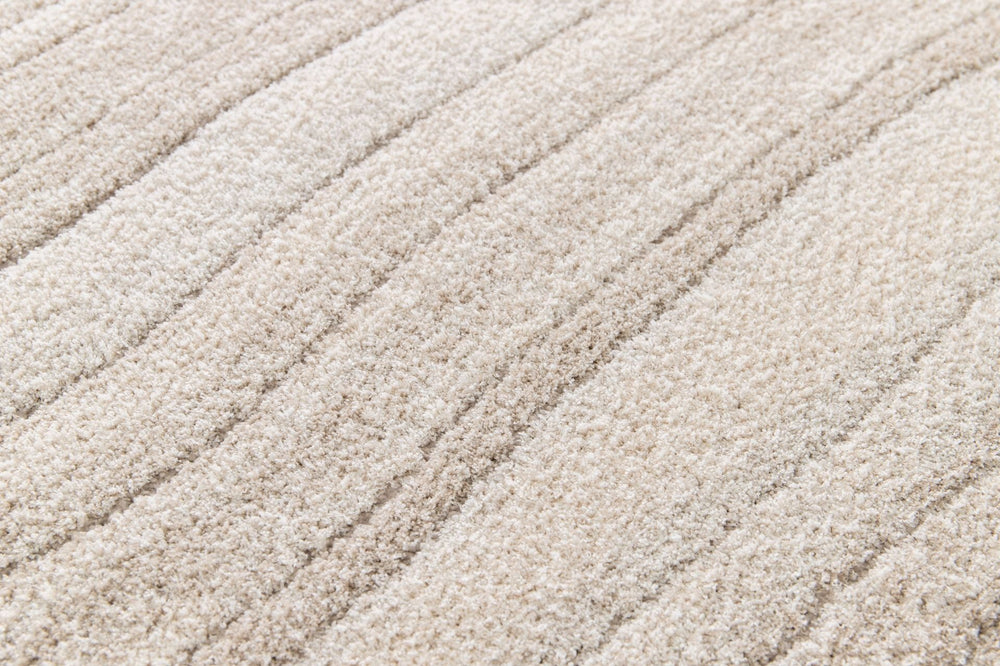 Close-up of plush beige rug surface with textured stripes.