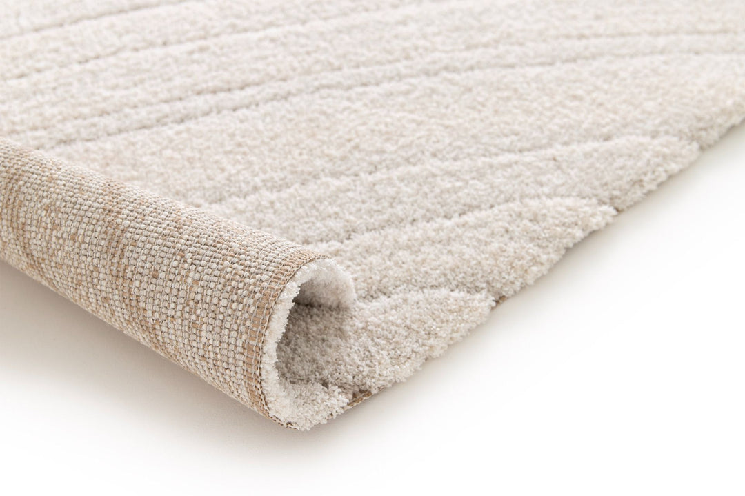 Rolled corner view of a cream rug with subtle textured lines.