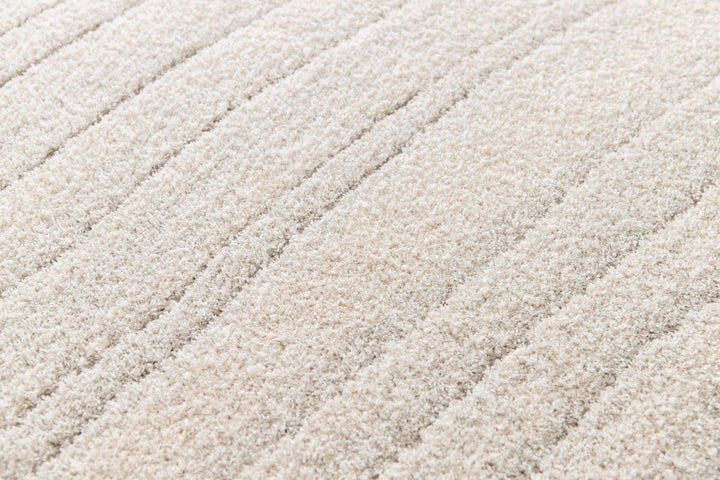 Close-up of soft cream rug surface showing plush lines.