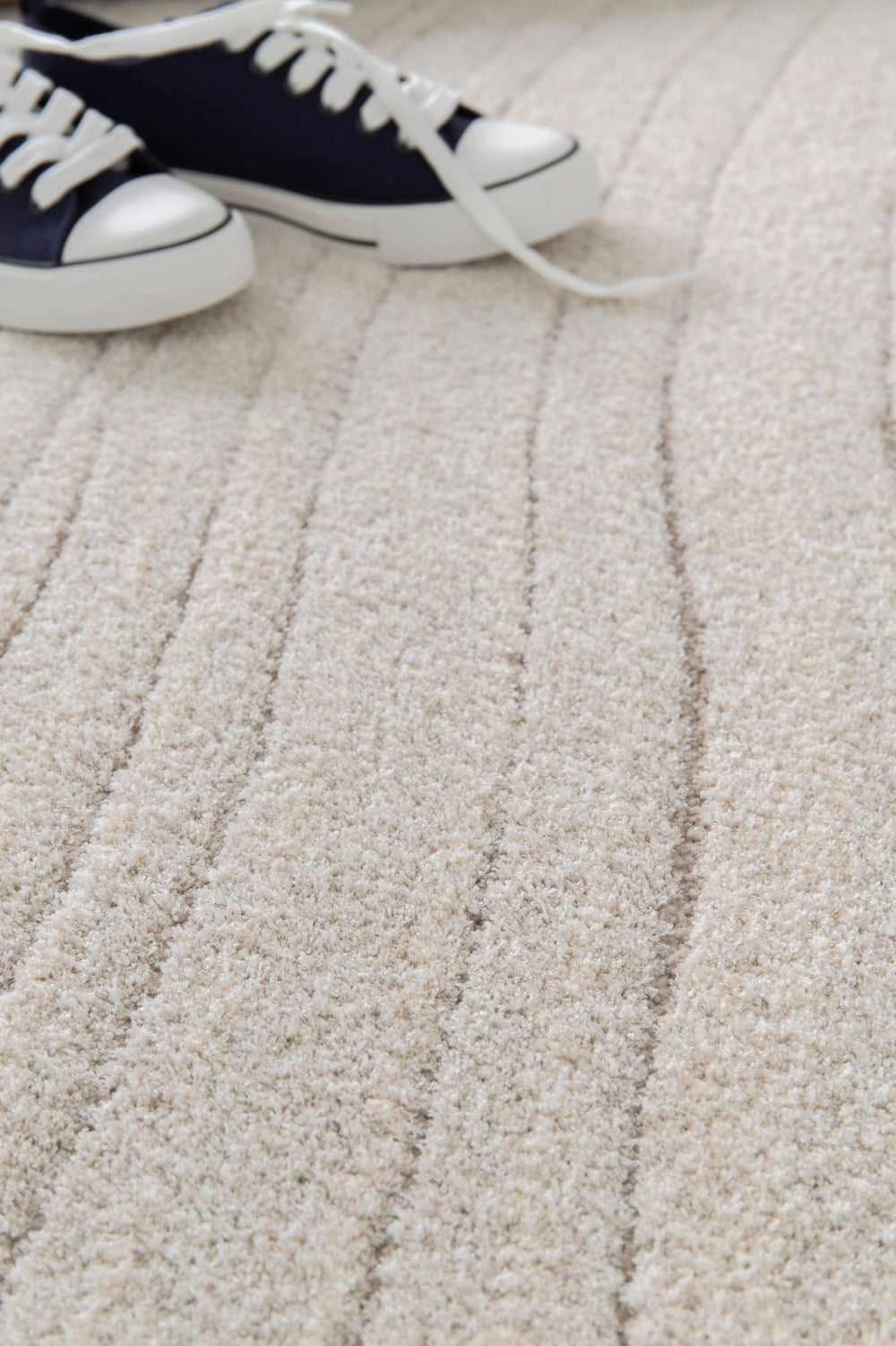 Cream rug with subtle stripes styled with navy sneakers.