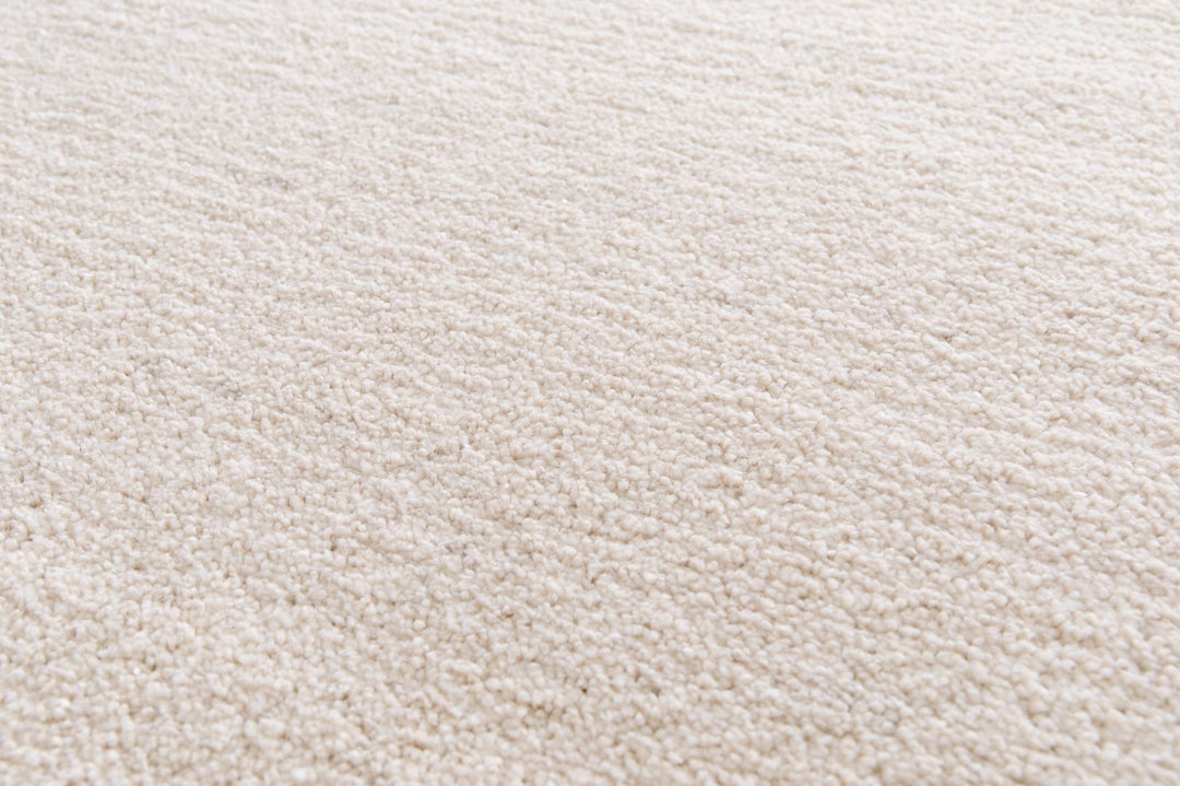 Close-up of beige rug corner showing surface texture.