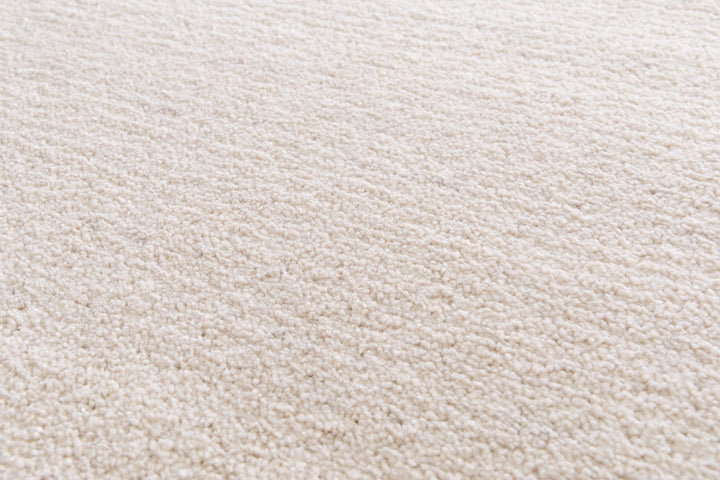 Close-up of beige rug corner showing surface texture.