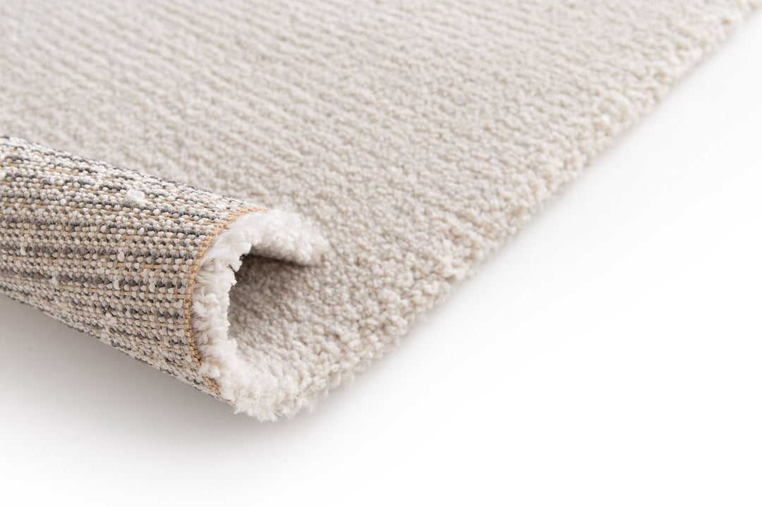 Close-up of the underside of a beige rug showing woven backing.