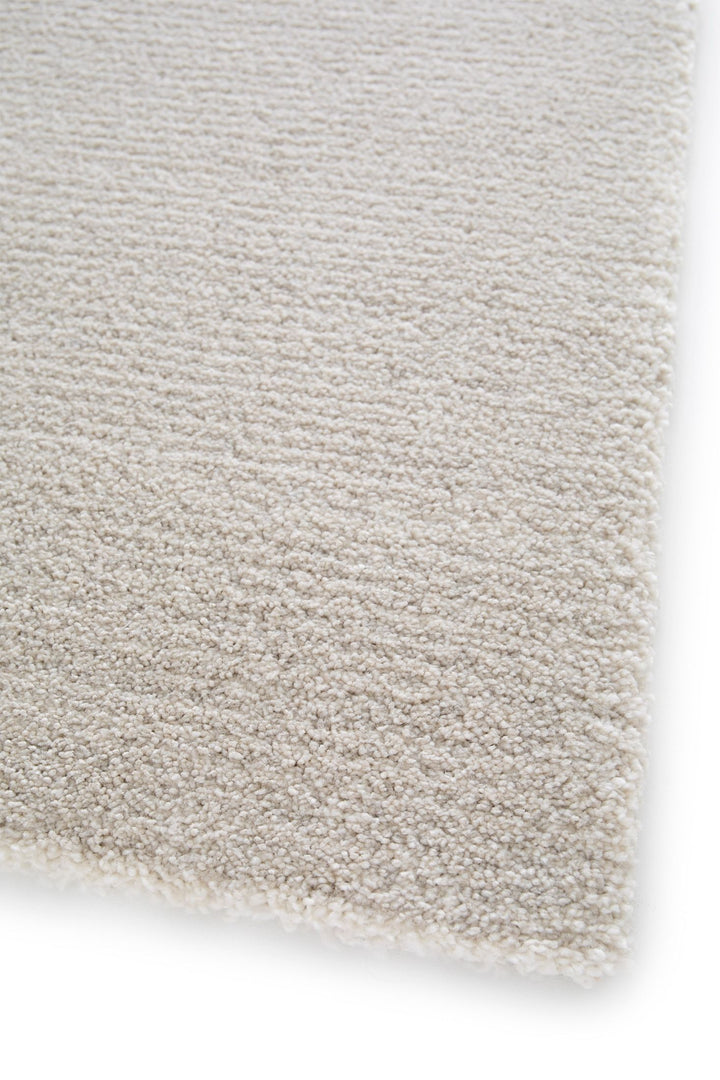 Detailed corner view of a soft beige rug texture.