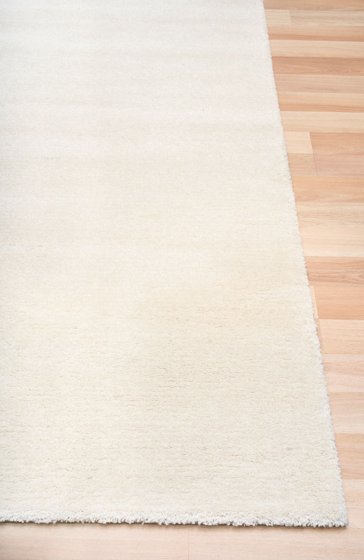 Detailed close-up of beige rug corner edge.