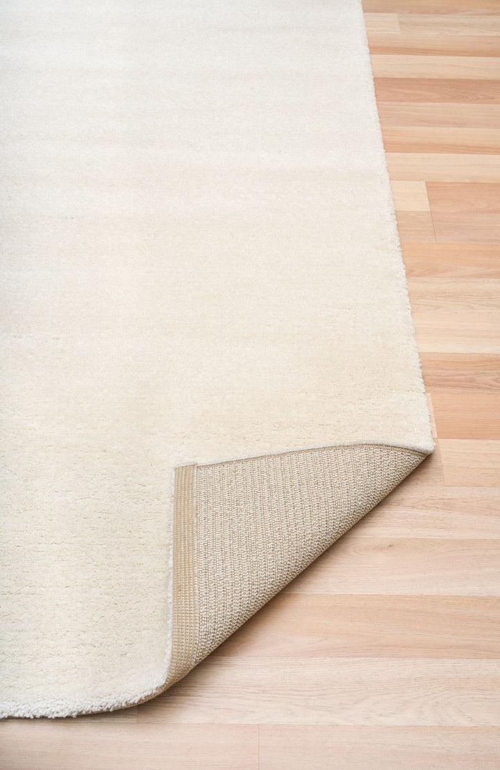 Angled corner view of beige rug showing texture and weave.