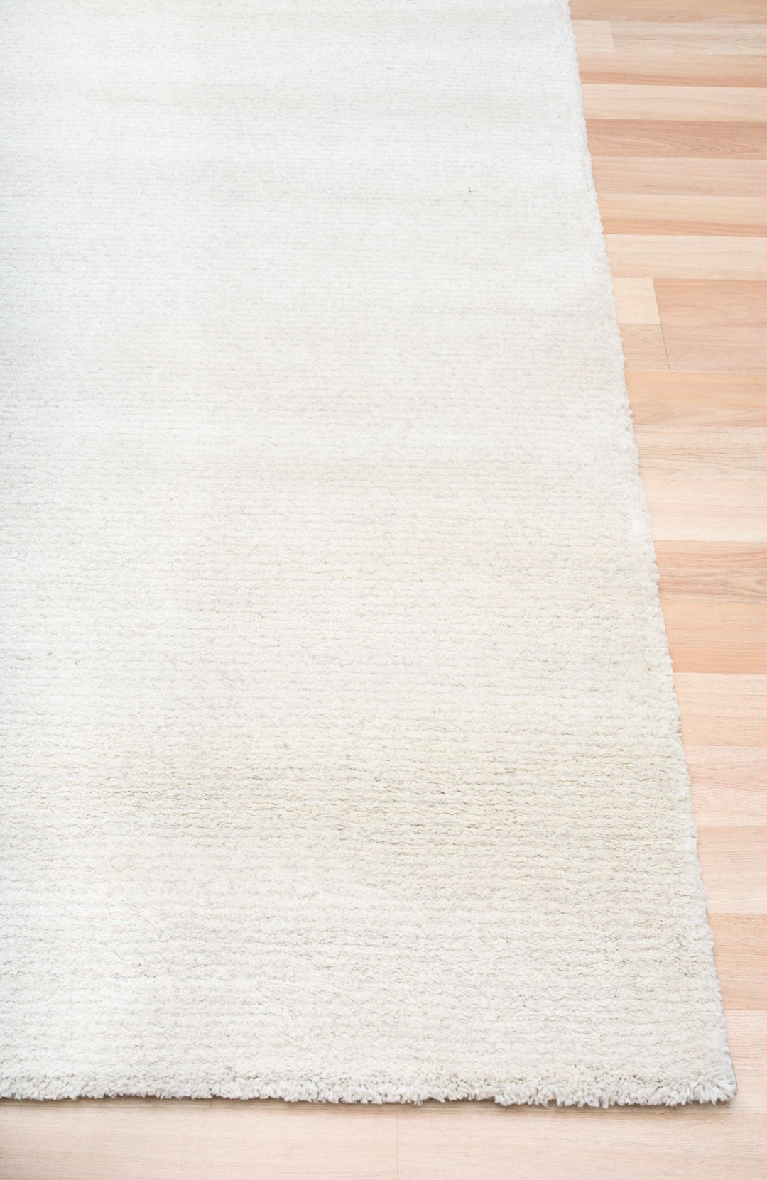 Close-up of a white textured rug on a wooden floor