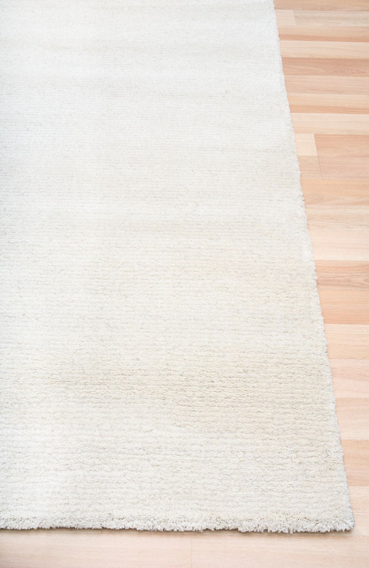 Close-up of a white textured rug on a wooden floor