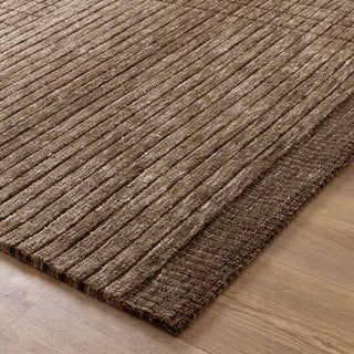 A corner view of a dark brown textured rug with a linear grid design on a wooden floor.